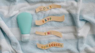 A striped towel with a bottle of suncream and a sign saying 'Don't skip the sunscreen' on it