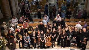 A wide shot photo of a large group of musicians, composers and the public.