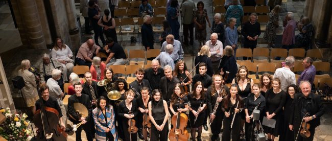 A wide shot photo of a large group of musicians, composers and the public.