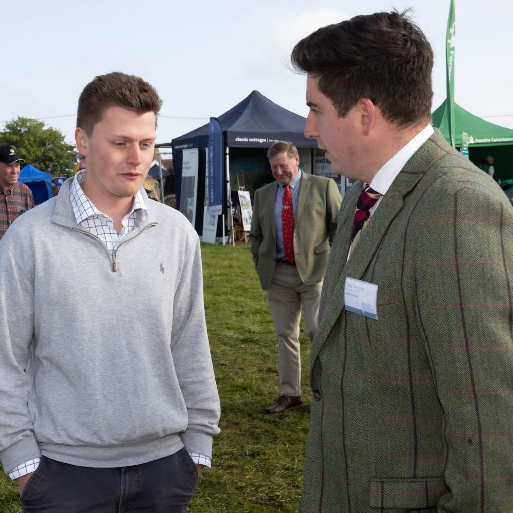 Two men in conversation outside on grass.