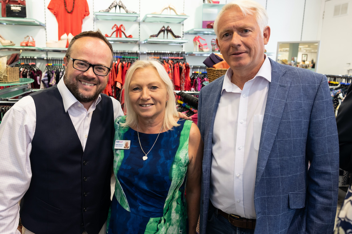 Three people stood in the Guild Care shop.