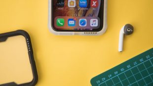 Yellow table top with open smart phone, a bluetooth ear bud, phone case, and cutting board sat on top. Creating engaging content tips on Title Sussex