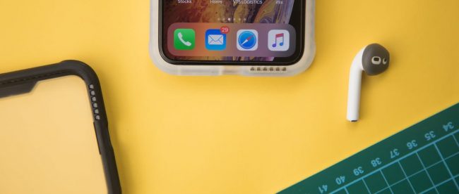 Yellow table top with open smart phone, a bluetooth ear bud, phone case, and cutting board sat on top. Creating engaging content tips on Title Sussex