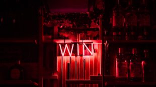Neon red sign reading 'WIN' on the wall in a dark room. Sussex heart charity wins Kings Award for Voluntary Service