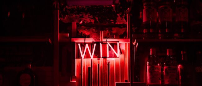 Neon red sign reading 'WIN' on the wall in a dark room. Sussex heart charity wins Kings Award for Voluntary Service