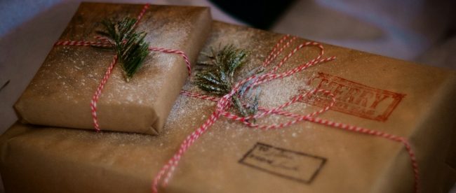 last Christmas posting dates UK courier services 2023 - see the list on Title Sussex www.titlesussex.co.uk A stack of brown paper packages with red and white bows and stamps printed on them. Last Christmas posting days UK