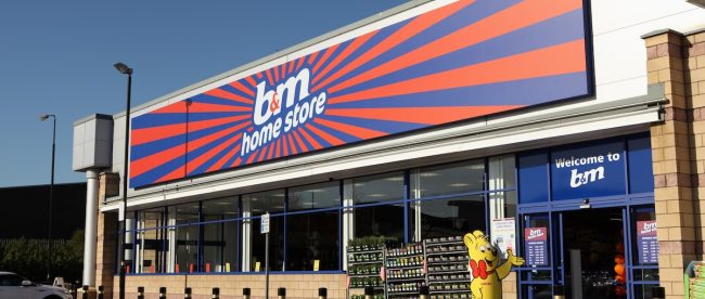 Bright B & M store front, orange and blue sign, under a blue sky. B&M Worthing store set to open in February 2024