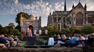 Image shows outdoor theatre taking place with backdrop of Arundel Castle behind the performers