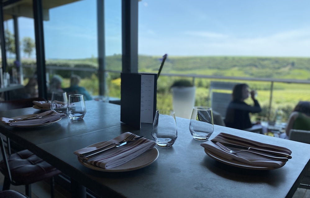 View of restaurant table and green vista blurred in the background. Rathfinny Tasting Room - a room with a view - Title Sussex www.titlesussex.co.uk